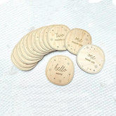 Set of round wooden cards with milestone text on a textured white surface