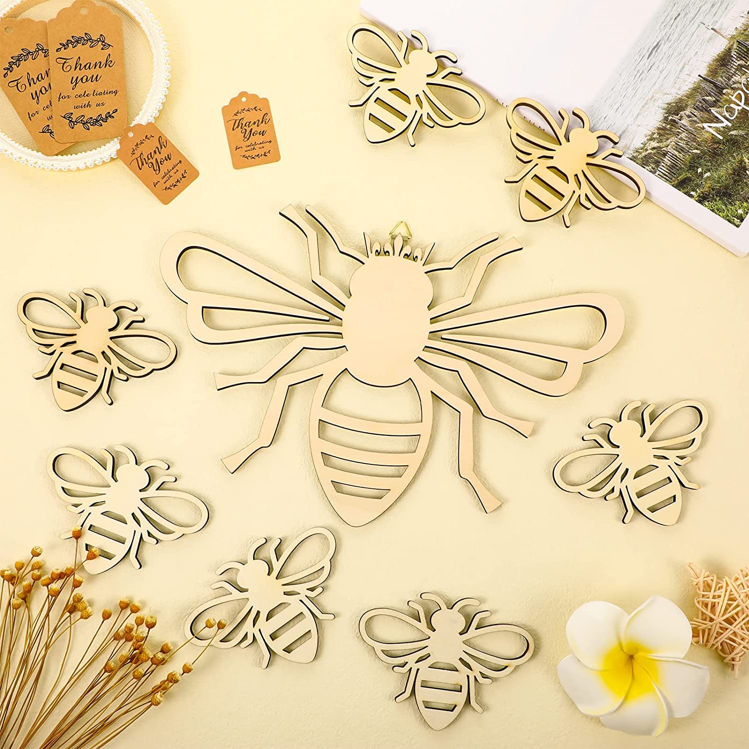 Wooden bee-shaped decorations on a beige surface with flowers and cards.