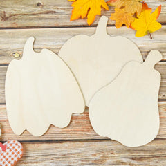 Three wooden pumpkin shapes on a wooden surface with fall leaves.