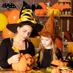Woman and child in Halloween costumes carving pumpkins together.