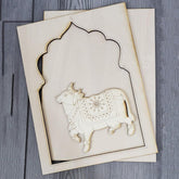Decorative wooden cutout of a cow with intricate patterns on a gray surface