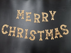 Decorative wooden letters spelling 'Merry Christmas' on a dark background