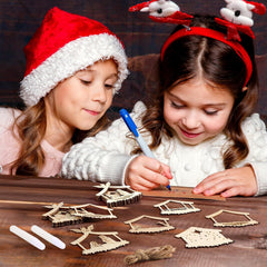 Two children wearing festive hats and reindeer ears, engaged in a craft activity on a wooden table.