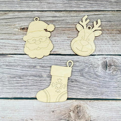 Three wooden Christmas ornaments shaped like Santa, a reindeer, and a stocking on a rustic wooden surface.