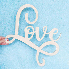 Wooden 'love' sign held against a light blue background
