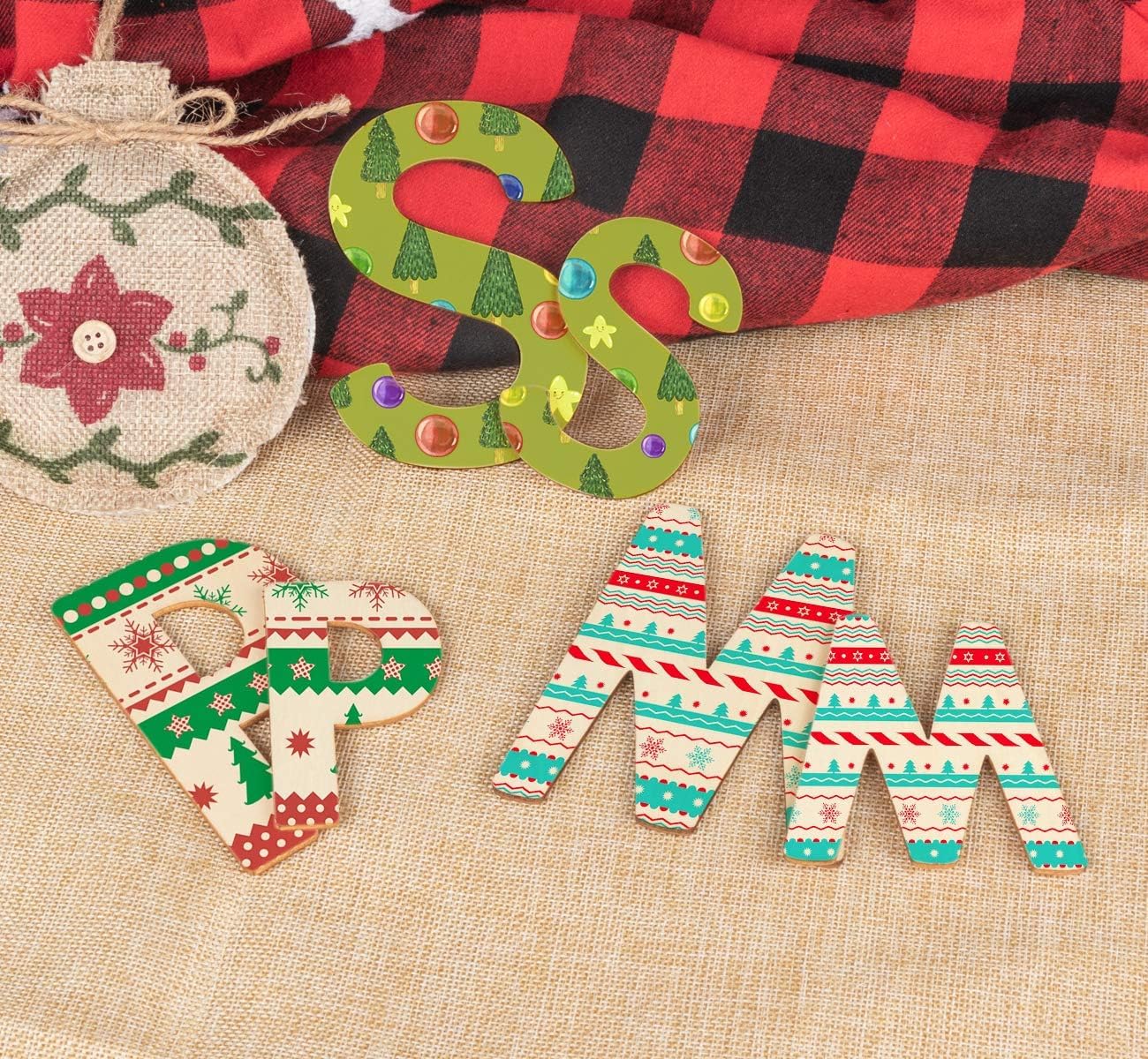 Decorative Christmas letters spelling 'Merry' on a textured surface with a plaid fabric background.