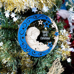 Decorative ornament for 'Baby's First Christmas' on a decorated tree.