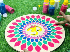 Colorful mandala on a wooden board with paint bottles and brushes on grass