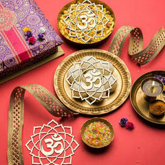 Decorative setup with gold plates, bowls, and a purple gift box on a red background.