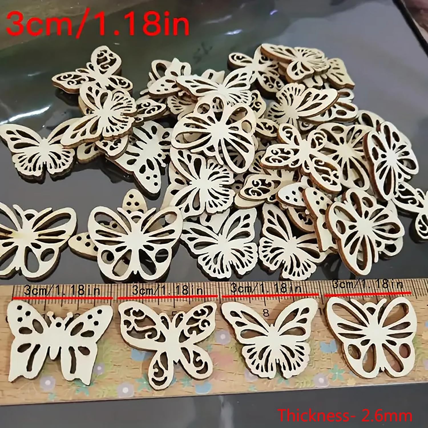 Wooden butterfly decorations with a ruler for scale on a reflective surface.