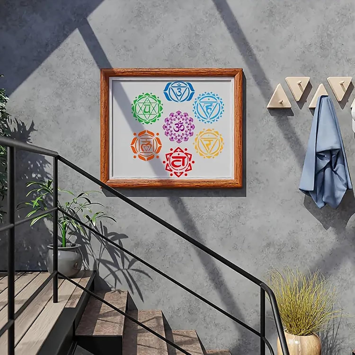 Framed artwork of chakra symbols on a concrete wall with plants and a towel.