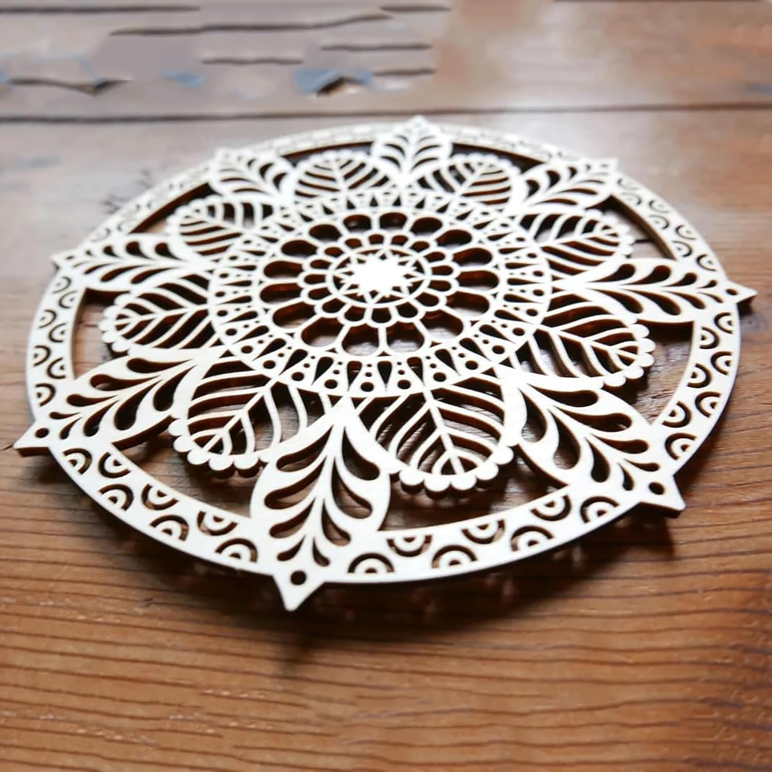 Decorative wooden coaster with intricate cut-out design on a wooden surface