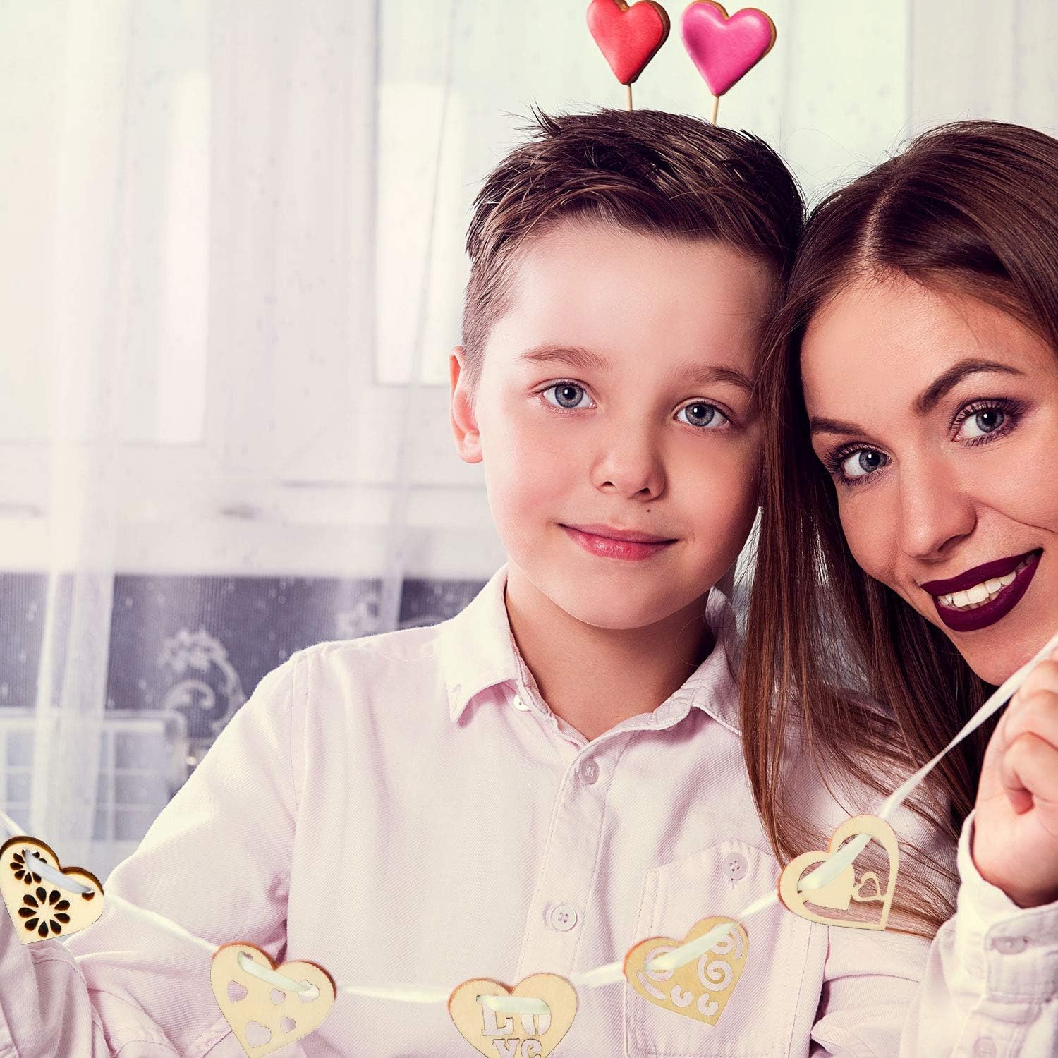 Woman and child with heart decorations on their heads, smiling at the camera.