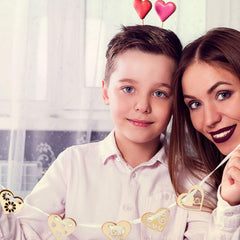 Woman and child with heart decorations on their heads, smiling at the camera.