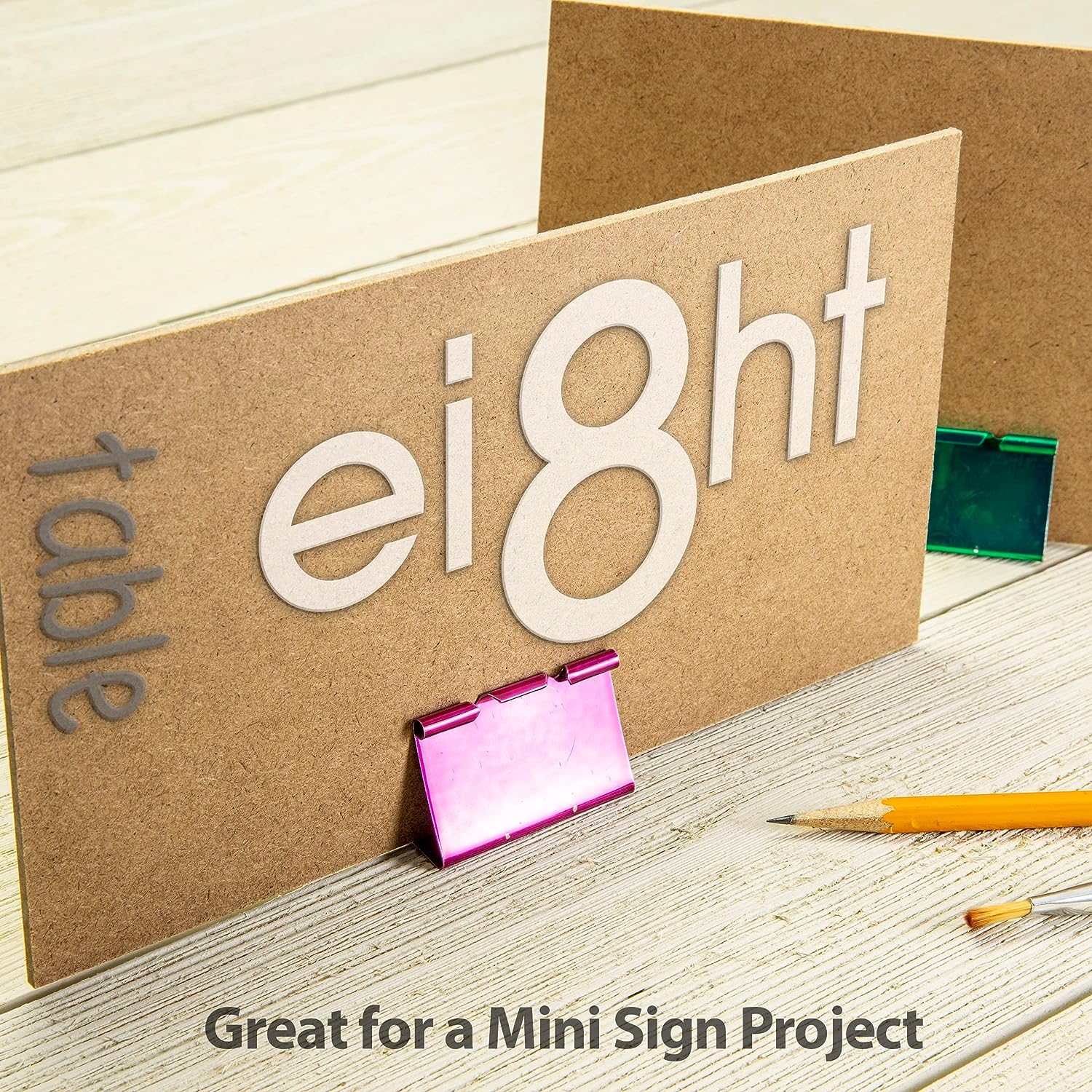 Cardboard sign with 'eight' and 'table' text on a wooden surface with stationery items.