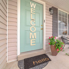 Front door with 'WELCOME' sign, doormat, and potted plant on a porch.