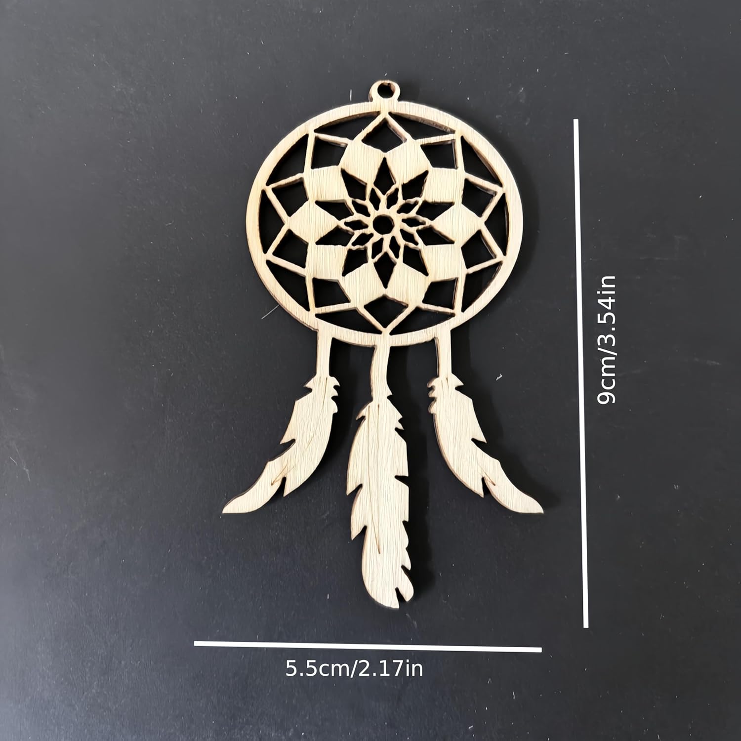 Wooden dreamcatcher ornament with feathers on a black background, showing measurements.