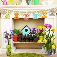 Decorative shelf with flowers, birdhouse, and bunting in a spring-themed setting.