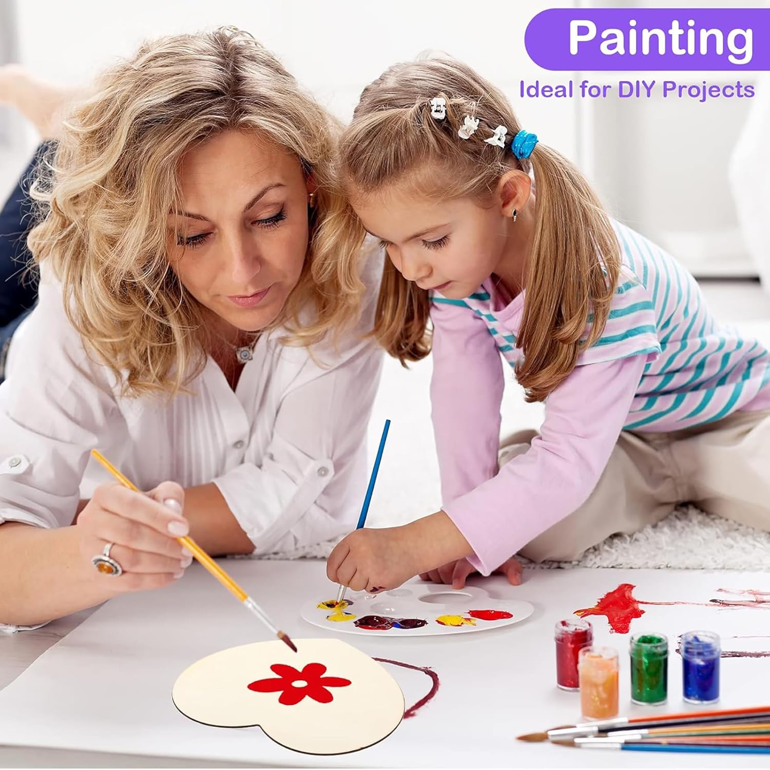 Woman and child painting together on a table with art supplies.