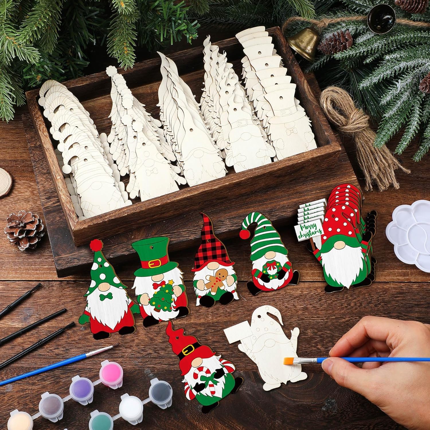 Wooden Christmas tree ornaments in a box with hand-painted gnomes on a wooden surface.