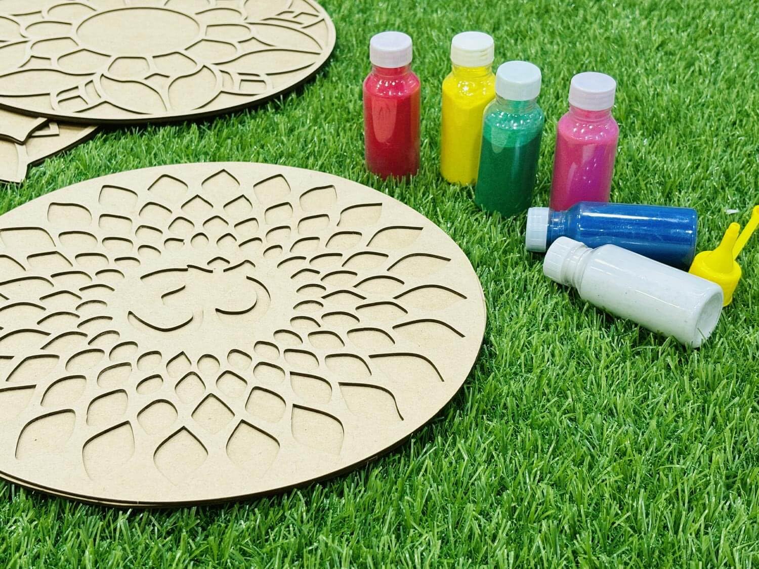 Wooden circular templates with paint bottles on grass