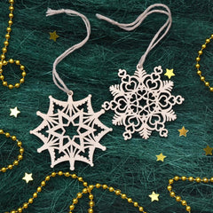 Decorative snowflake ornaments on a textured green surface with gold beads and stars.