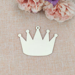 White crown-shaped object on a textured beige surface with pink flowers in the background