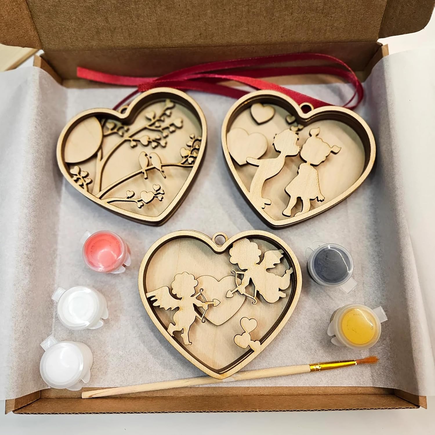 Wooden heart-shaped cutouts with paint supplies in a box