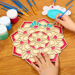 Wooden mandala being painted with colorful paint and brushes on a wooden table.