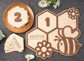 Wooden baby milestone cards with numbers and a bee design on a textured surface.