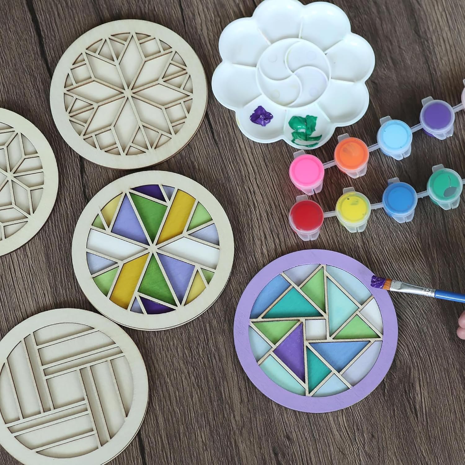 Decorative stencils with geometric patterns on a wooden surface, surrounded by paint and a brush.
