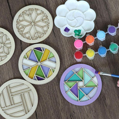 Decorative stencils with geometric patterns on a wooden surface, surrounded by paint and a brush.