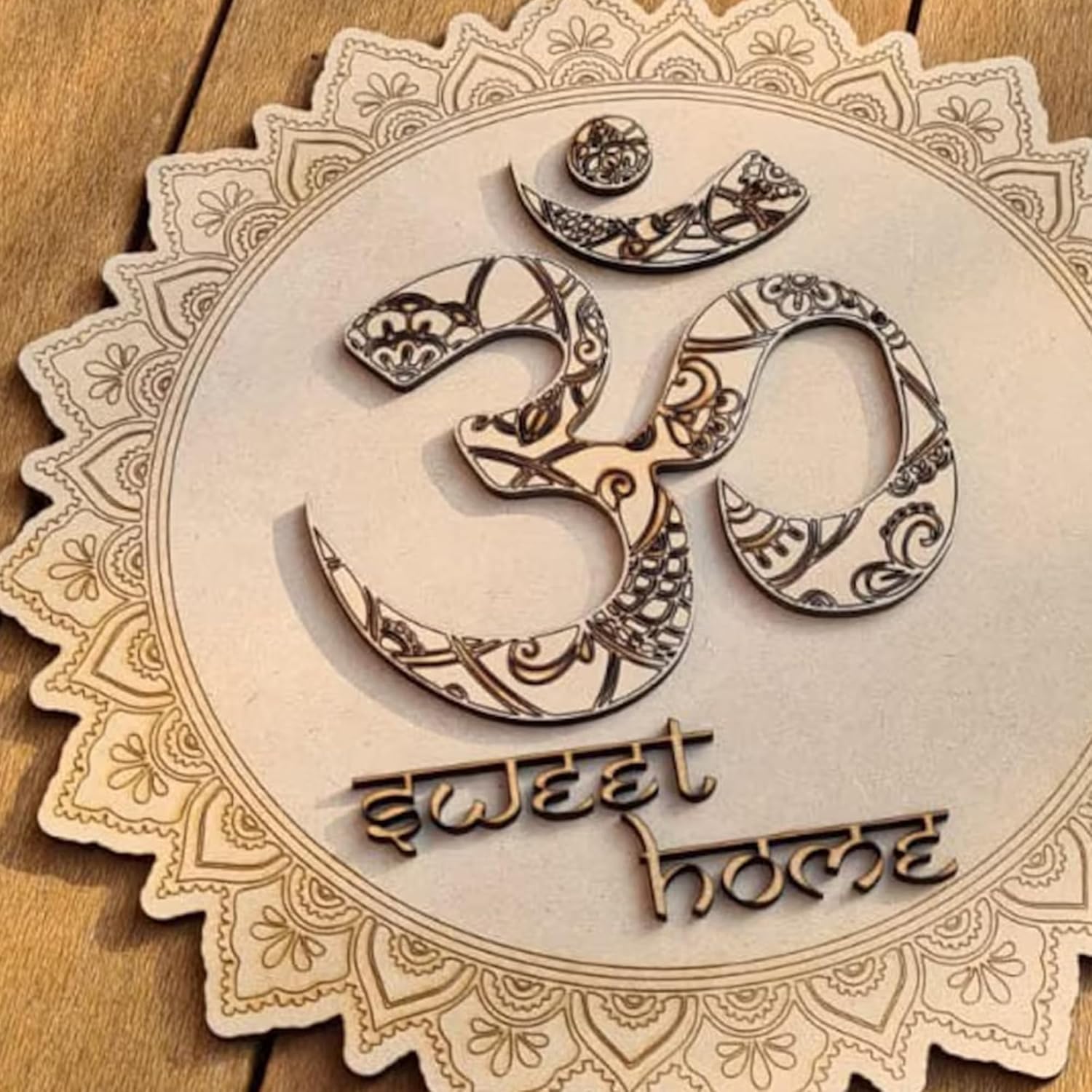 Decorative wooden sign with 'Om' symbol and 'sweet home' text on a wooden background