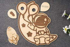 Wooden baby milestone plaque with astronaut design on a textured surface.