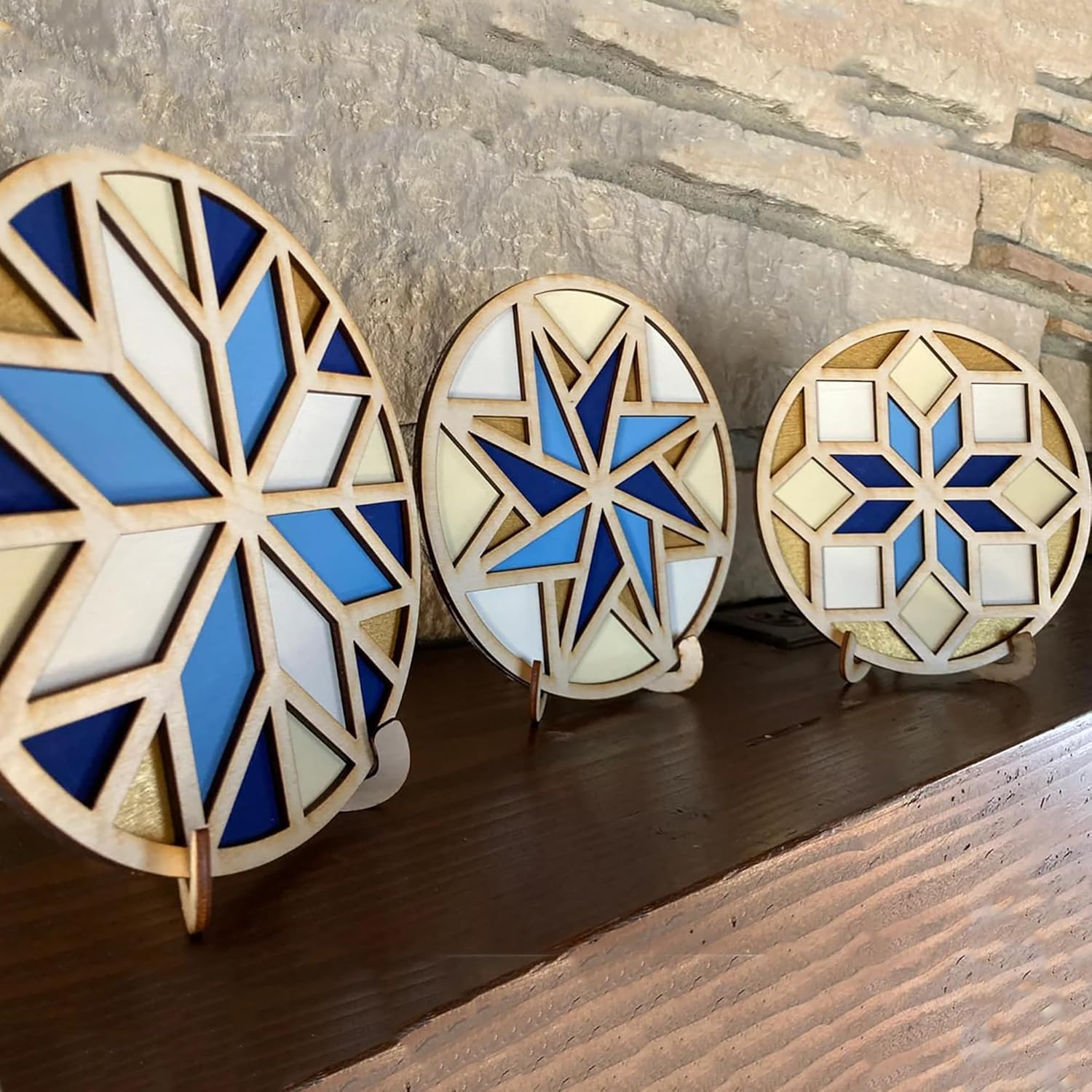 Three geometric wooden light fixtures with blue and white patterns on a wooden surface.