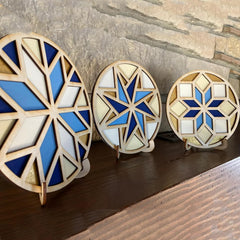 Three geometric wooden light fixtures with blue and white patterns on a wooden surface.