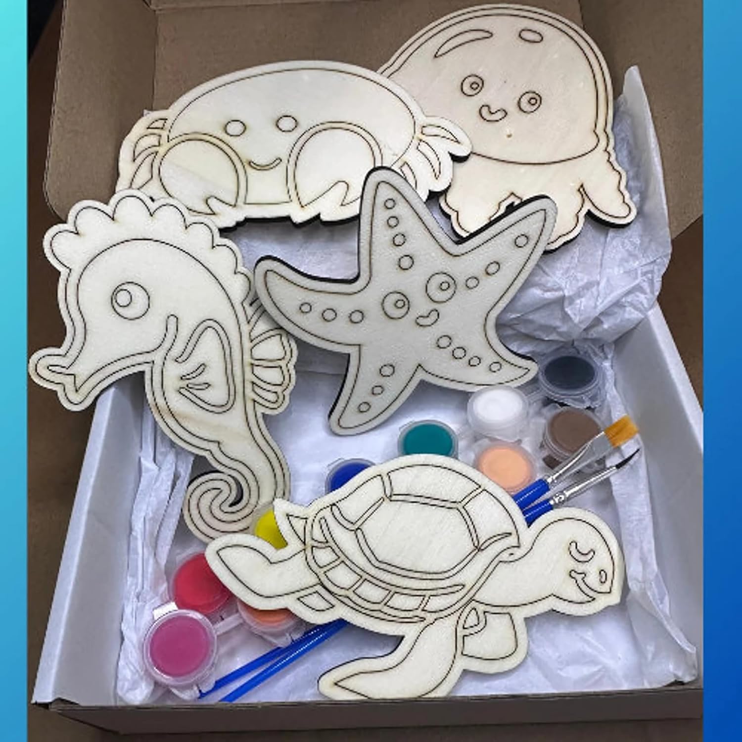 Wooden sea creature shapes with paint supplies in a box