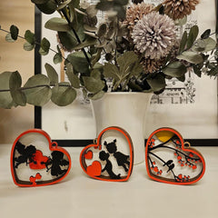 Heart-shaped decorative items with silhouettes of a couple and a heart, placed in front of a vase with flowers.