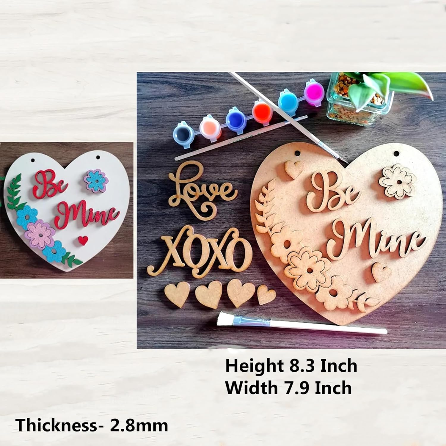 Wooden heart-shaped plaque with 'Be Mine' and 'Love XOXO' text, surrounded by paint bottles and brushes on a wooden surface.