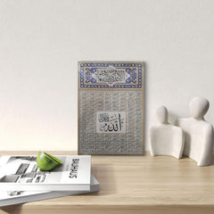 Decorative wall art with Arabic calligraphy on a wooden surface with a magazine and sculptures.