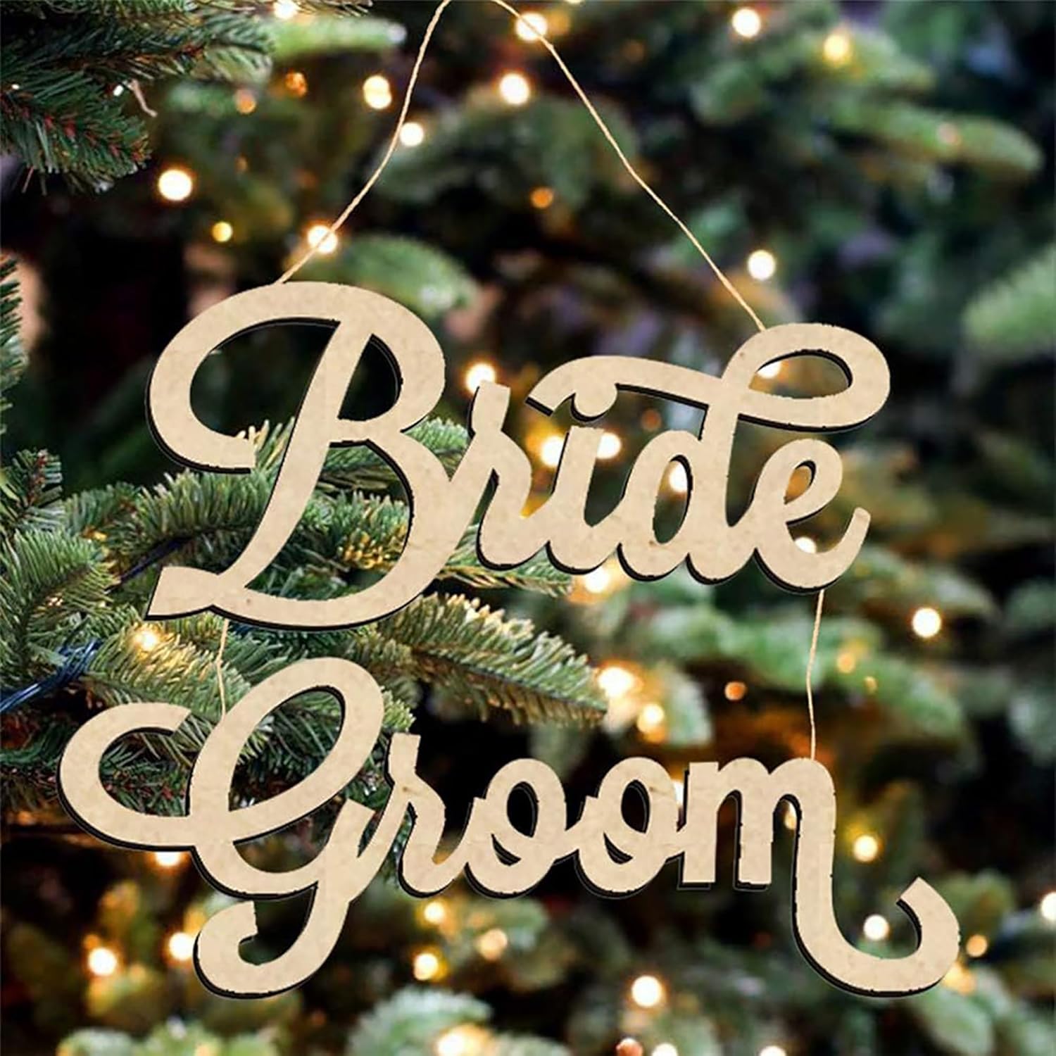 Wooden 'Bride Groom' sign hanging on a decorated Christmas tree with lights.