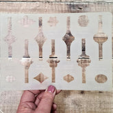 Decorative stencil with geometric patterns held by a hand on a wooden surface