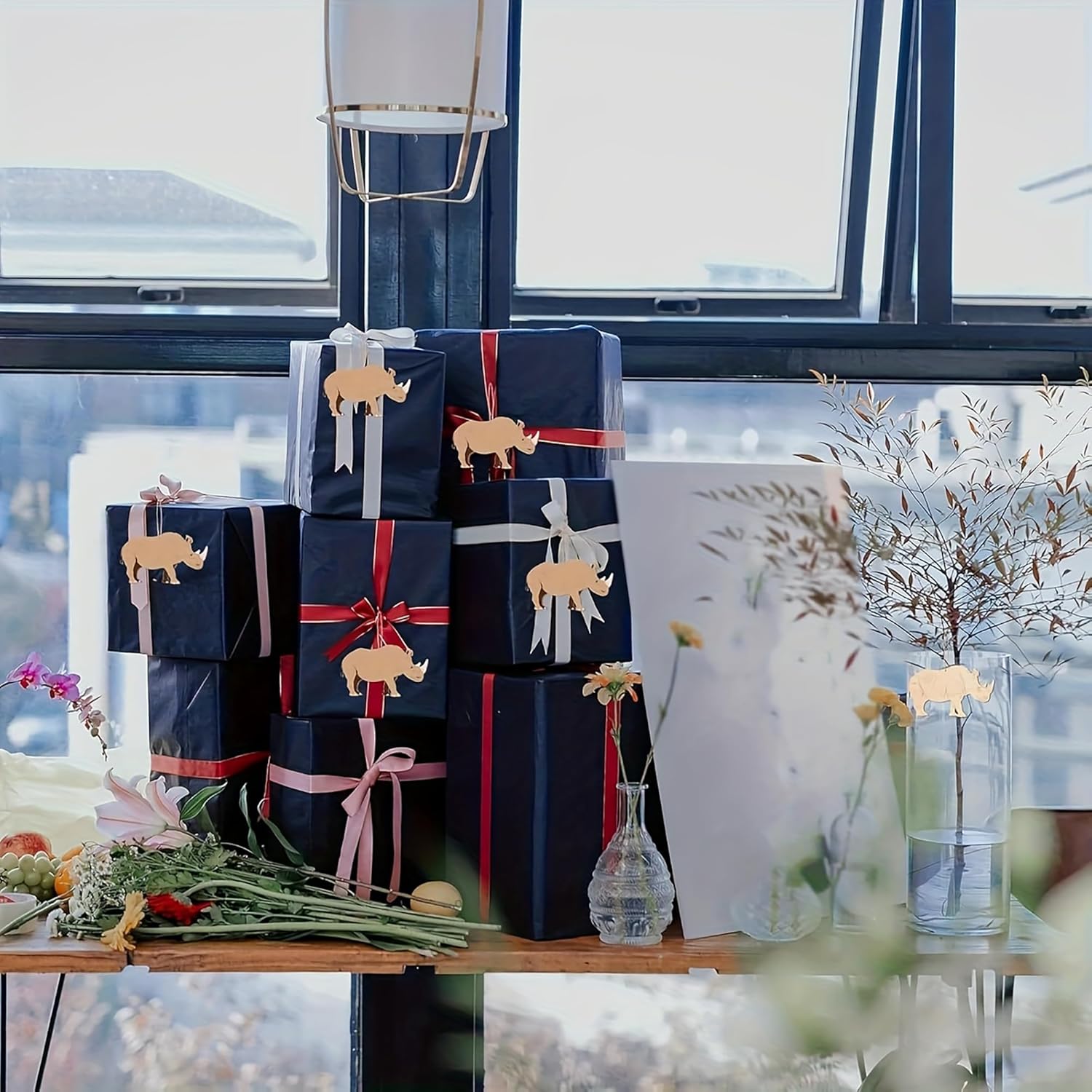 Stack of wrapped presents with decorative elephants on a table by a window