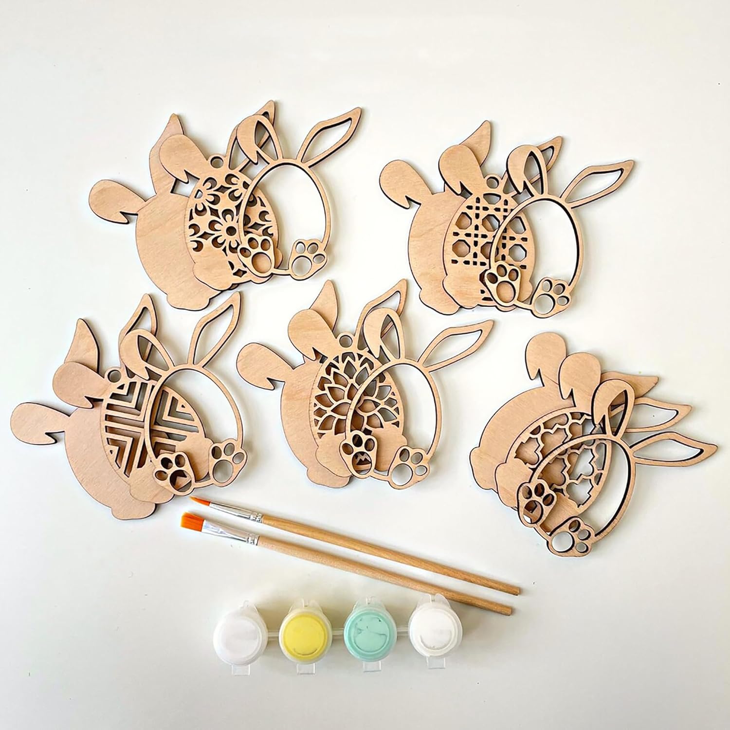 Set of wooden turtle-shaped cutouts with paintbrushes and paint on a white background