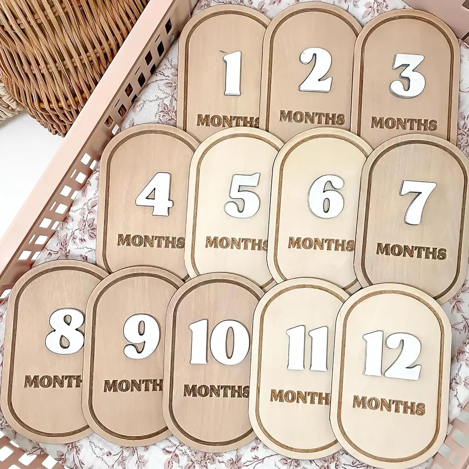 Wooden baby milestone markers with numbers 1 to 12 months on a floral background.
