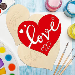 Heart-shaped wooden cutout with 'love' text on a blue surface with paint supplies.