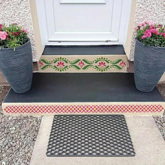 Decorative step with floral patterns on a door threshold, flanked by two potted plants.