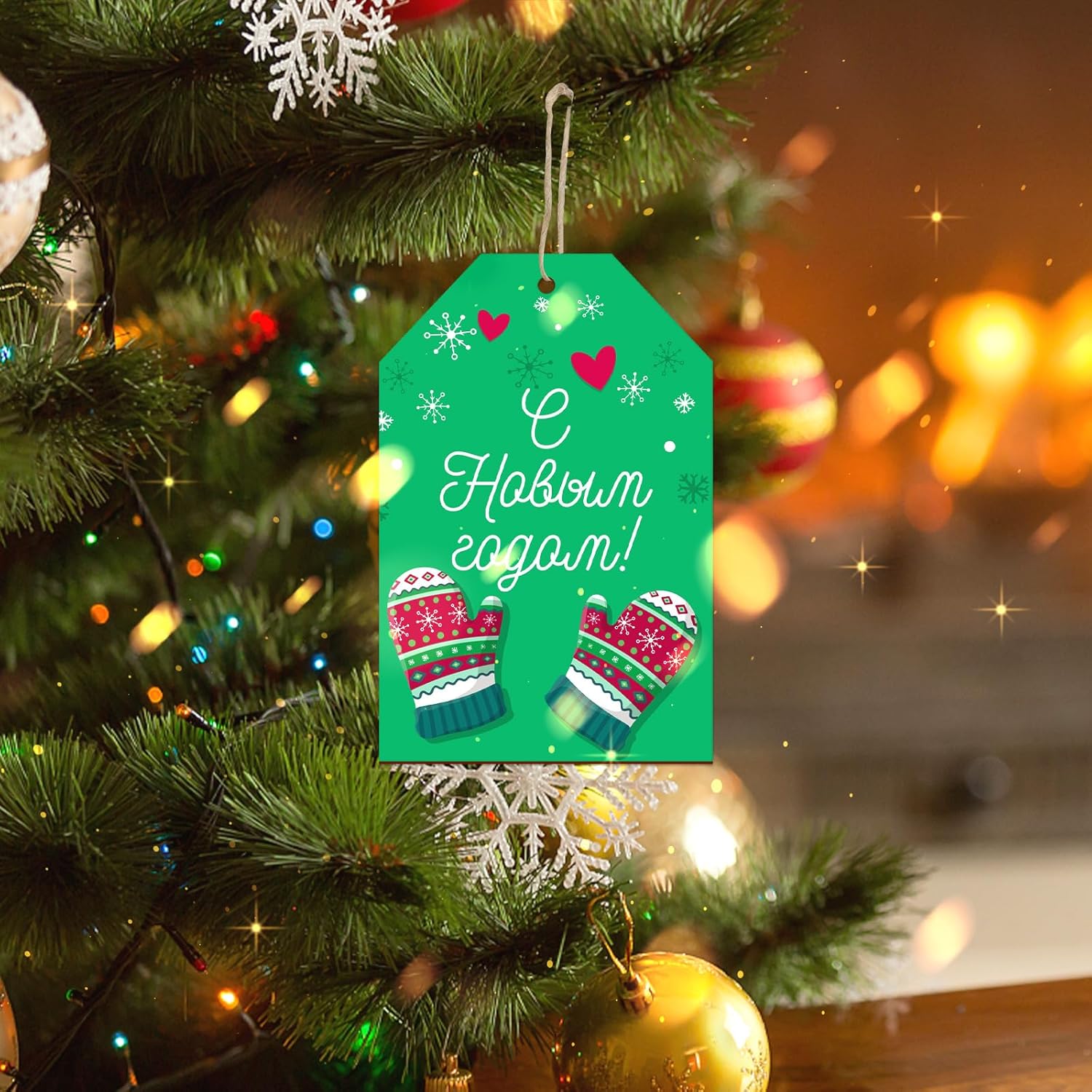 Decorative Christmas tag with mittens design hanging on a tree