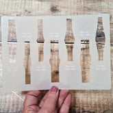 Hand holding a set of clear plastic templates on a wooden surface