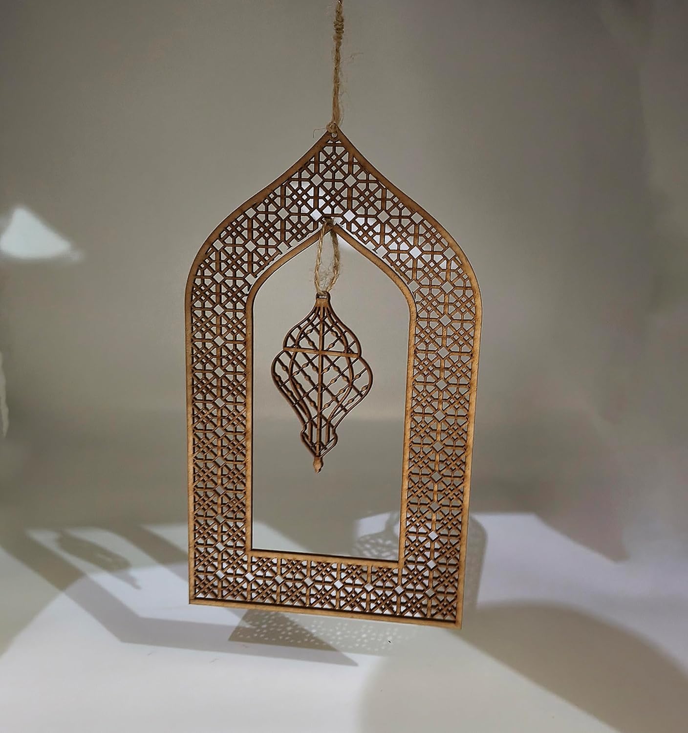 Decorative hanging mirror with intricate cut-out design on a neutral background